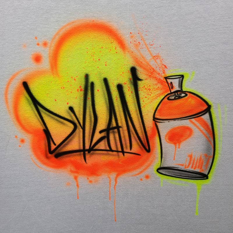 Custom airbrush shirt featuring a neon spray paint graffiti design with the name "Dylan" and a colorful spray can illustration in orange, green, and yellow.