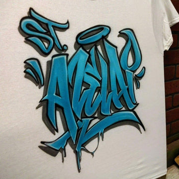 Side view of a custom graffiti shirt with wildstyle blue lettering, outlined in black, and a halo graphic above the name, designed in a bold and expressive street art style.